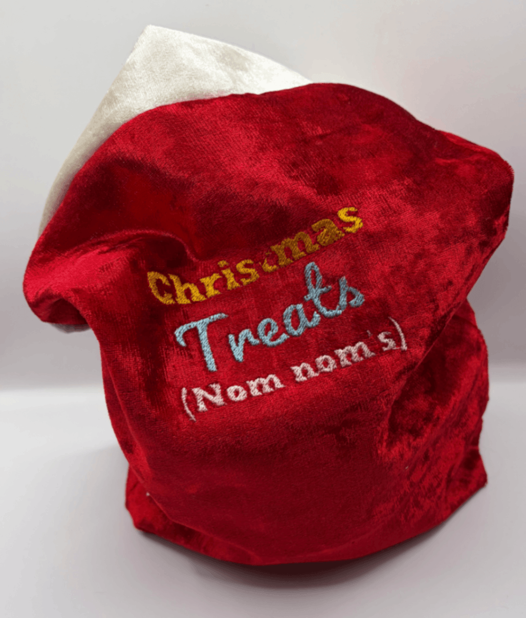 Close view of a red velvet Fur Baby Santa Sack with Christmas Treats design